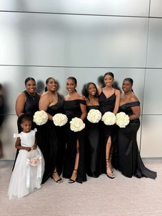 a group of women standing next to each other wearing black dresses and holding bouquets