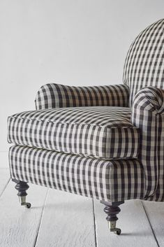 a black and white checkered chair sitting on top of a wooden floor next to a wall