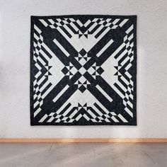 a black and white quilt hanging on the wall