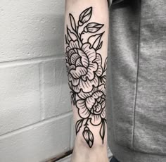 a black and white flower tattoo on the right arm, with leaves around it's edges