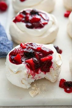 small desserts with berries and whipped cream are on a cutting board, ready to be eaten