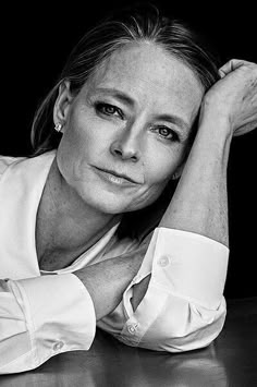 a black and white photo of a woman leaning on a table