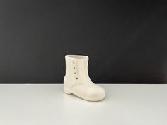 a white boot shaped vase sitting on top of a table