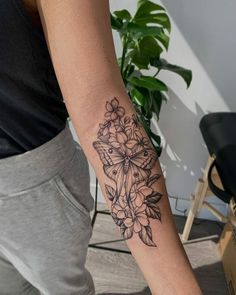 a woman with a tattoo on her arm holding onto a piece of paper that has flowers in it