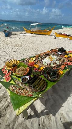 a table that has food on top of it at the beach with boats in the background