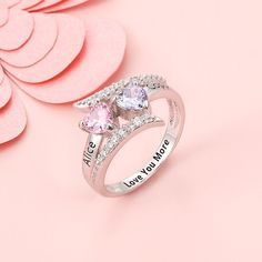 two heart shaped pink and white rings on top of a pink background with flowers in the background