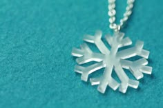 a silver snowflake necklace on a blue background