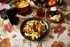 a black plate topped with pasta next to bowls of vegetables and other foods on a table