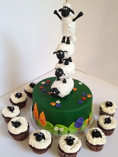 a cake with sheep on top and cupcakes around it in front of the cake