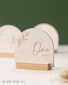 two wooden heart shaped place cards with the word, one table no written on them