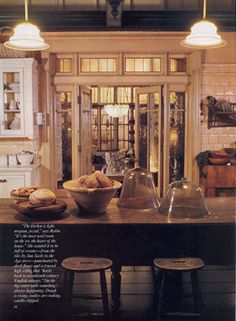 an old fashioned kitchen with two lamps above the table and some bread on the counter