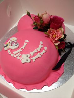 a pink cake decorated with sugar skulls and flowers