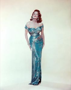 an old photo of a woman in a blue dress with her hands on her hips