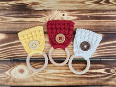 three crocheted baby hats with buttons on them sitting on top of a wooden table