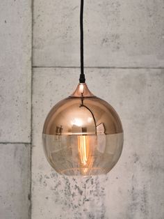 a light that is hanging from a wire in a room with concrete wall behind it