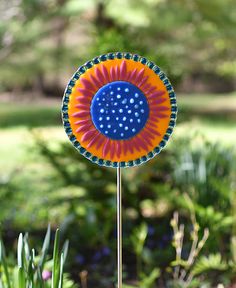 a blue, orange and yellow flower sitting on top of a metal pole