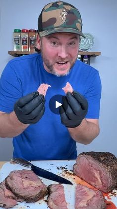 a man in blue shirt and black gloves holding up two pieces of meat