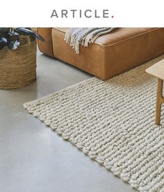 a living room with a couch, table and rugs on the floor in front of it