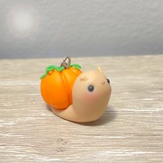 a small toy snail with an orange on it's back sitting on a table