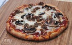 a pizza sitting on top of a cutting board covered in cheese and meat toppings