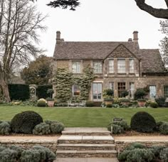 a large house sitting next to a lush green park filled with lots of trees and bushes