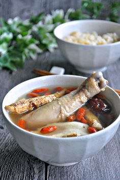 two white bowls filled with food on top of a wooden table next to chopsticks