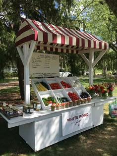 a white and red striped awning on top of a table filled with fruits and vegetables