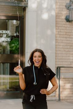 a woman in black shirt and pants holding up a sparkler with one hand while standing on sidewalk