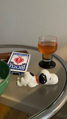 a glass of beer sitting on top of a table next to a small dog figurine