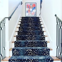 a stair case with blue and white designs on the carpet, next to a painting