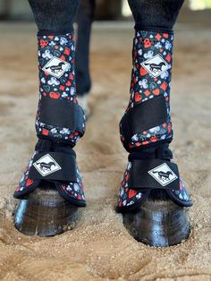 the legs and feet of a person wearing black boots with skulls on them, standing in sand