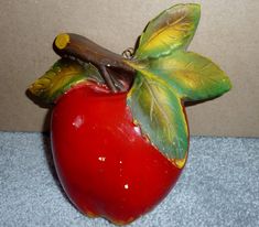 a red apple with green leaves and a stick sticking out of it's side