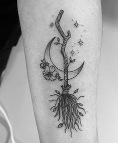 a black and white photo of a tree with roots on the leg, in front of a clock