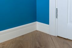 an empty room with blue walls and white trim on the door, next to a wooden floor