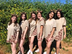 a group of young women standing next to each other wearing giraffe print dresses