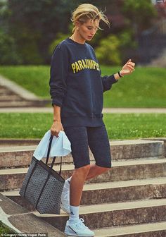 a woman walking down some steps carrying a bag