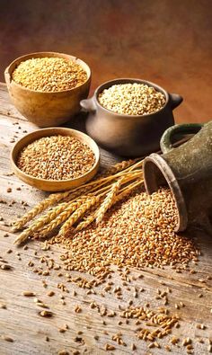 three bowls filled with grains on top of a wooden table