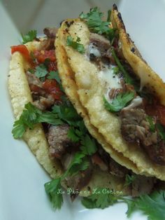 three tacos with meat, tomatoes and parsley