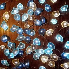 many blue and white glass flowers on a wooden surface with string lights attached to them