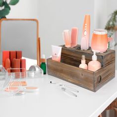 an assortment of beauty products are displayed on a table in front of a mirror and potted plant