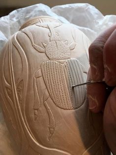 a person is carving a shoe out of clay with a small brush and glue on it