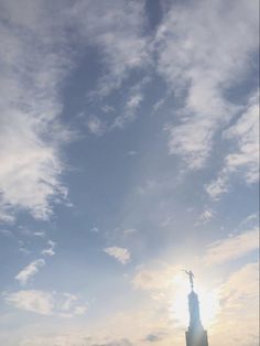 the statue of liberty is silhouetted against a blue sky with clouds in the foreground