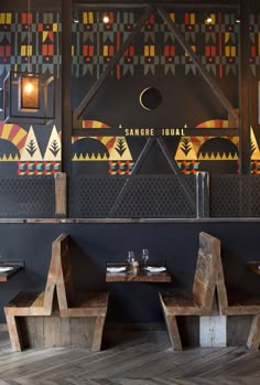 the interior of a restaurant with wooden tables and benches in front of an artistic mural