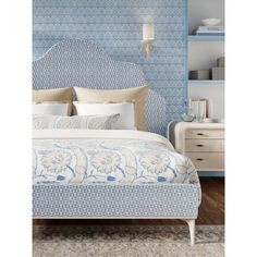 a bed with blue and white wallpaper next to a night stand in a bedroom