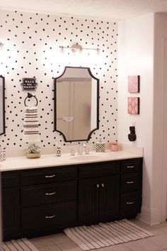 a bathroom with black and white polka dot wallpaper on the walls, two sinks and mirrors