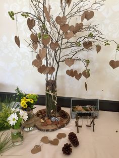 a table topped with a vase filled with lots of flowers and hearts hanging from the branches