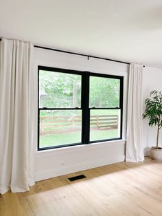 an empty room with large windows and white curtains