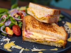 two grilled sandwiches are sitting on a plate next to a salad