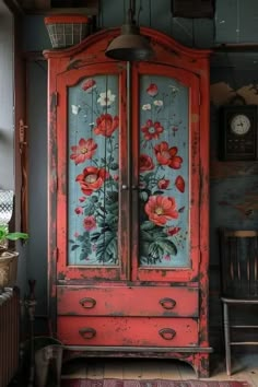 an old red armoire with flowers painted on it