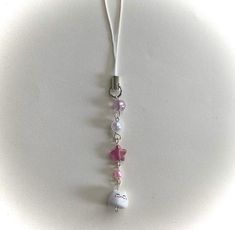 a white necklace with pink and white beads hanging from it's end on a cord